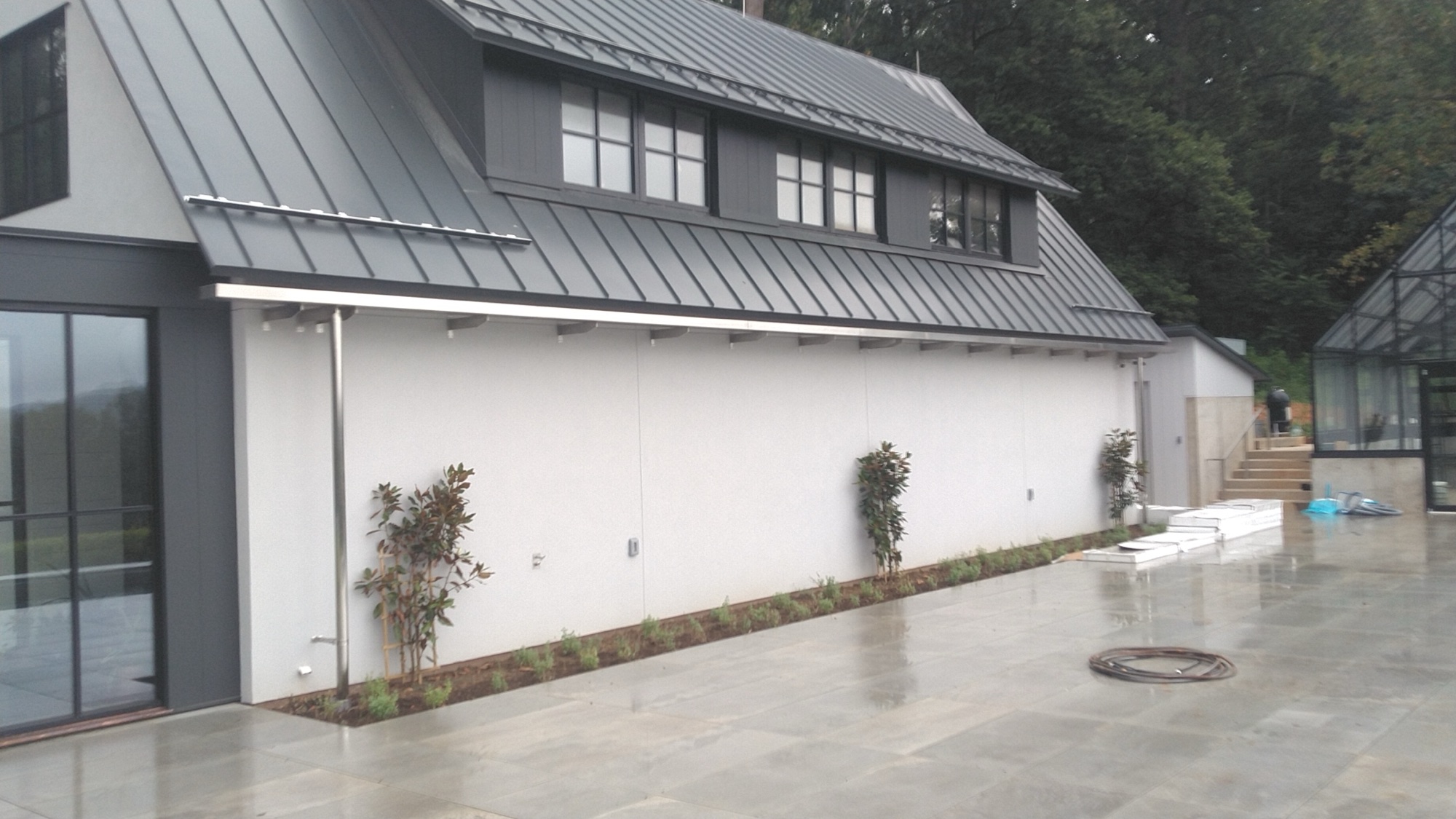 Custom stainless steel eyebrow awning brackets along the farmhouse roofline