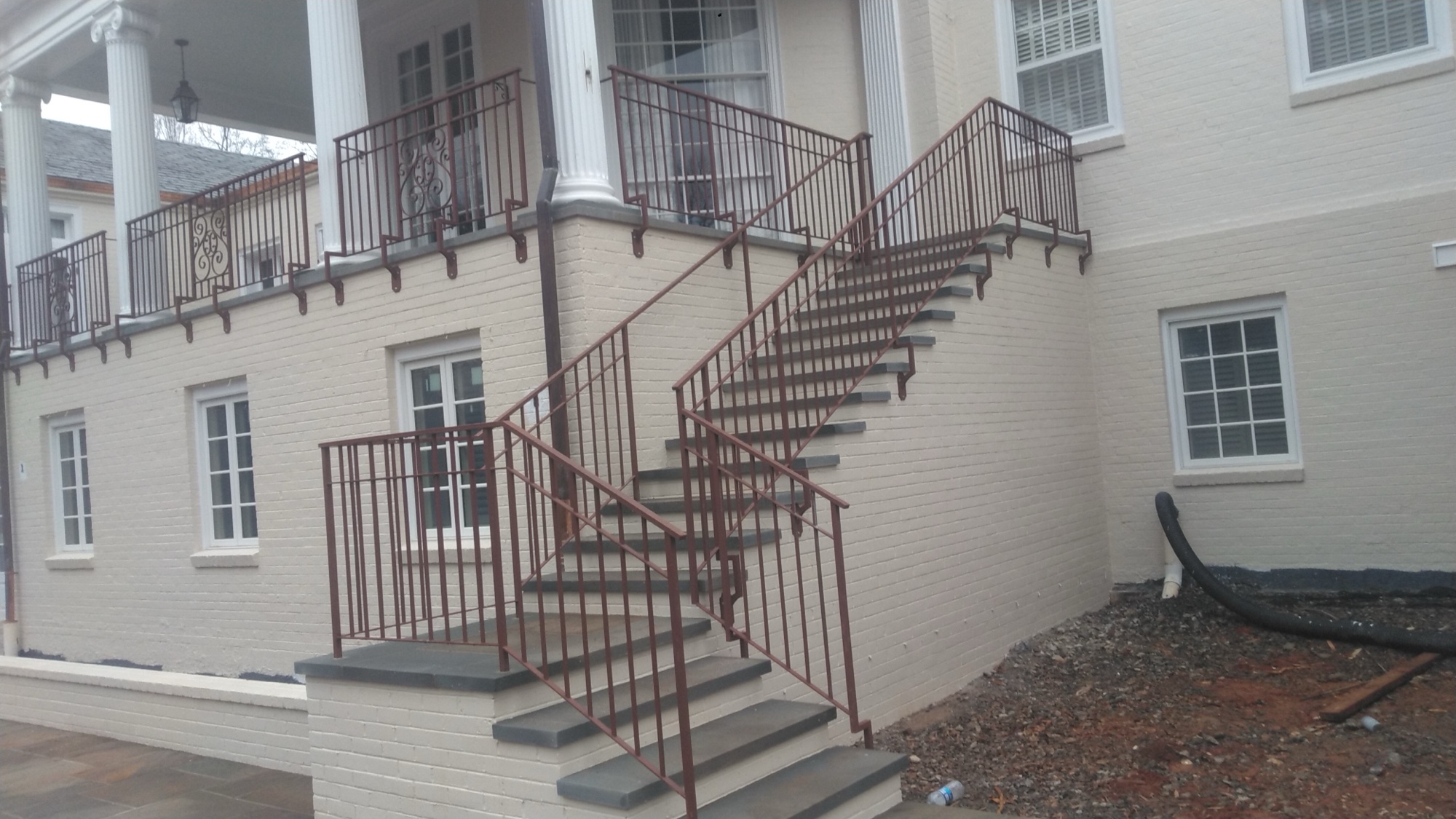 Wider view of the mansion with grand staircase and monogrammed railings