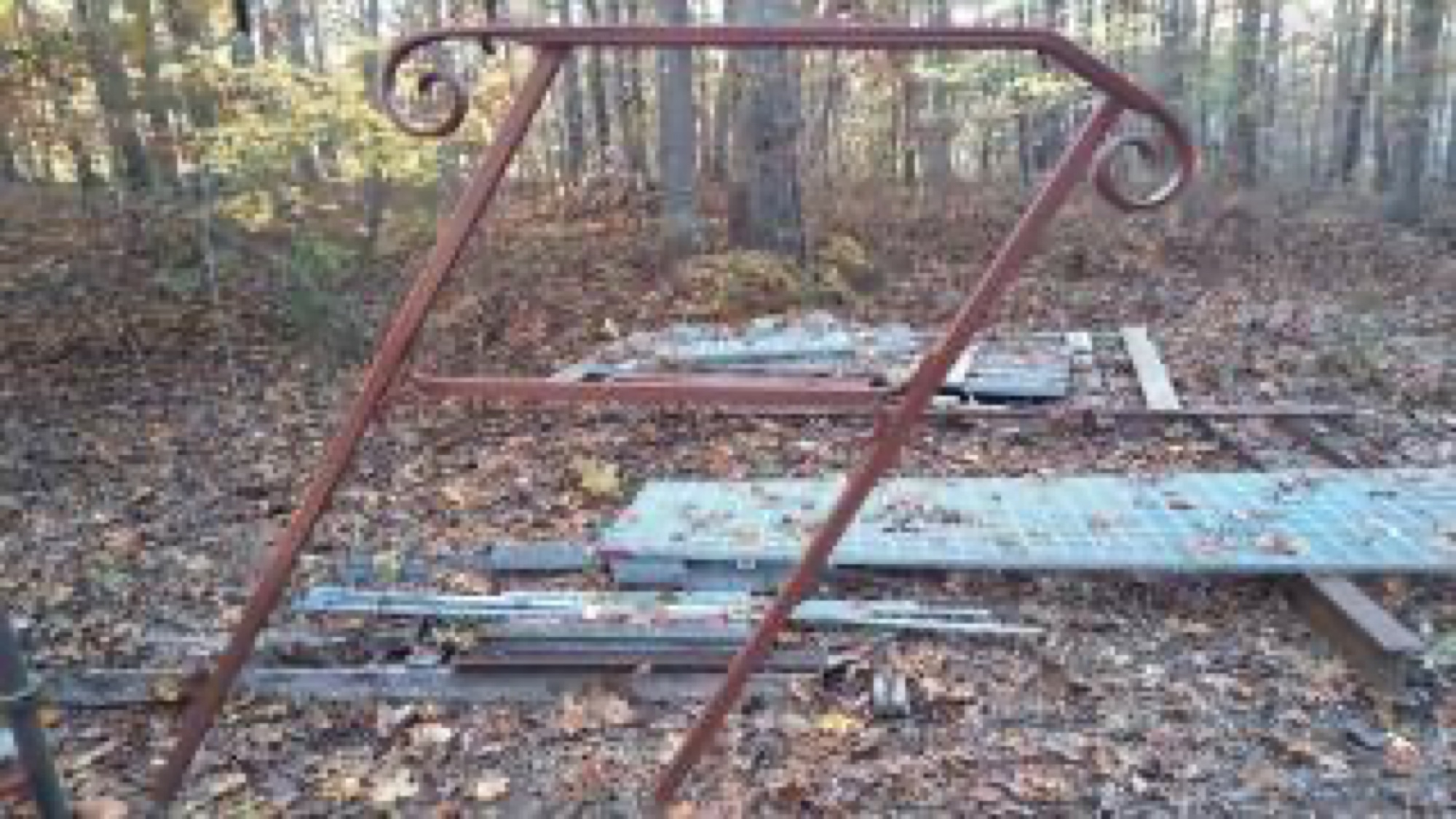 Rusted scroll-topped iron arbor waiting to be restored